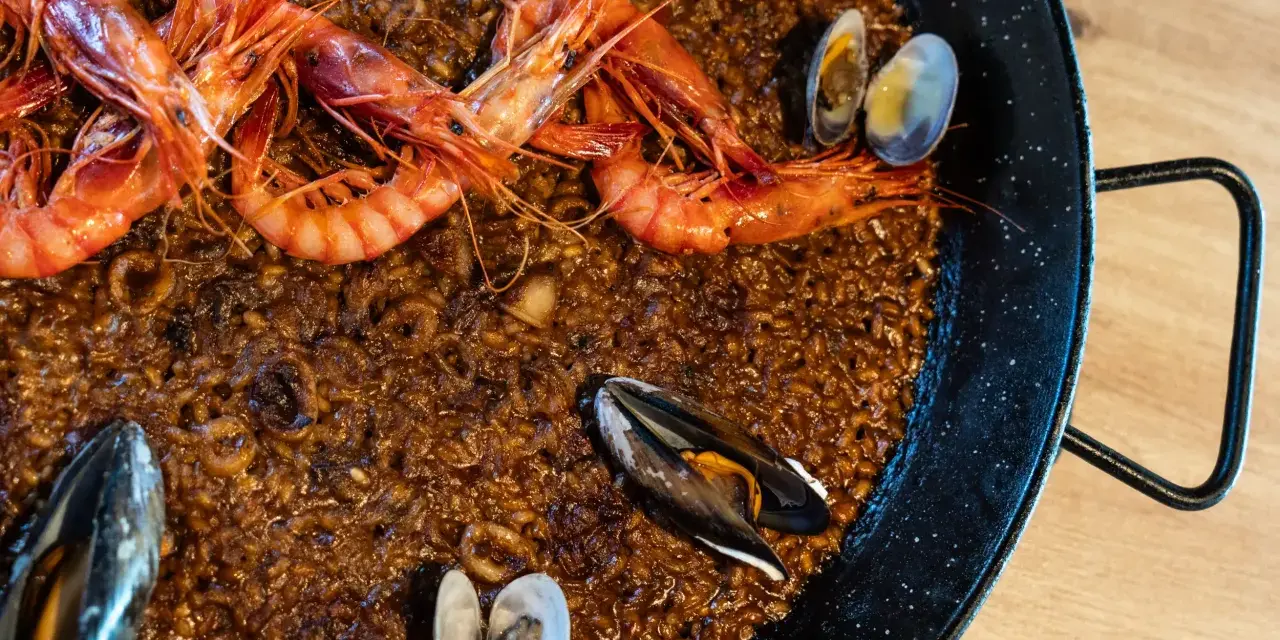 Paella de marisco con gambas rojas, mejillones y almejas sobre arroz dorado.