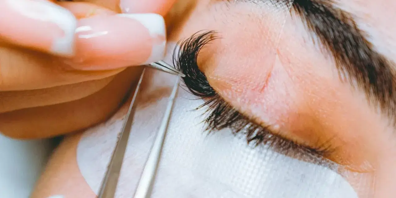 Precyzyjne przedłużanie rzęs: porównanie rzęsy 2d i 3d. Stylistka z perfekcyjnym manicurem dokłada kępki.