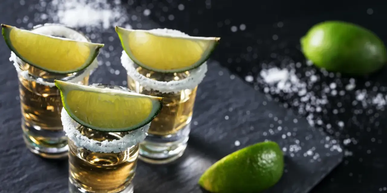 Szklanki z tequilą, ozdobione solą i ćwiartkami limonki. Idealne do picia z limonką, gdy zastanawiasz się, z czym pić tequilę.