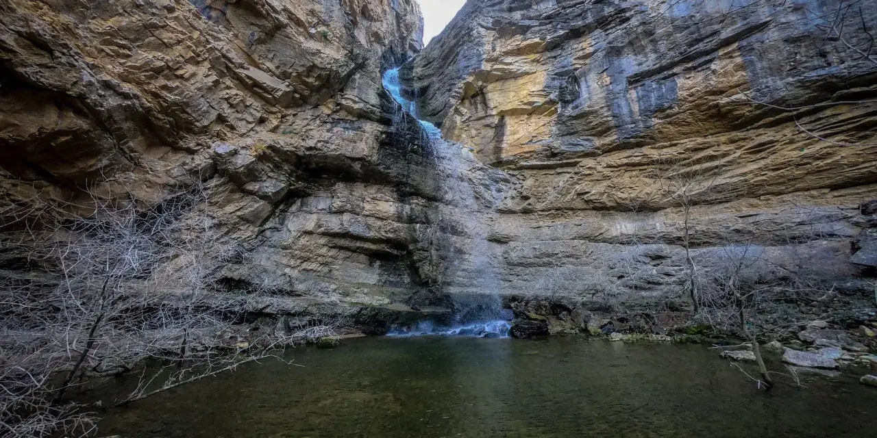 La cascada del Gollorio cae entre imponentes paredes rocosas, formando un estanque sereno.