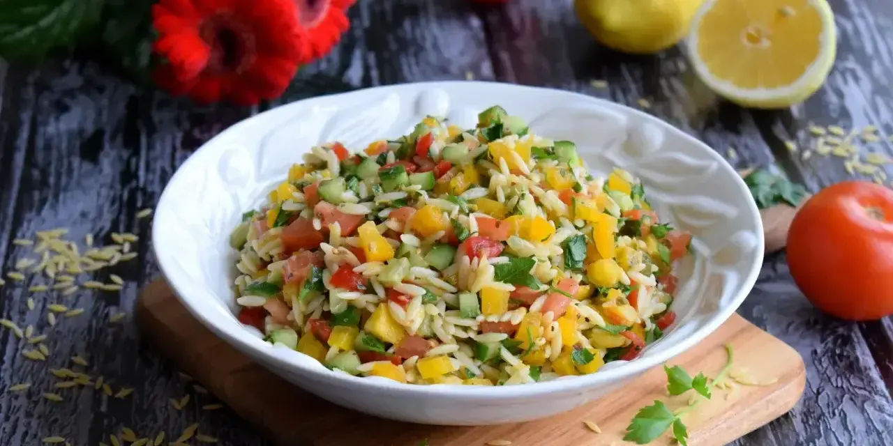 Kolorowa sałatka z makaronem orzo, pomidorami, ogórkiem i papryką. Idealna na letni obiad.