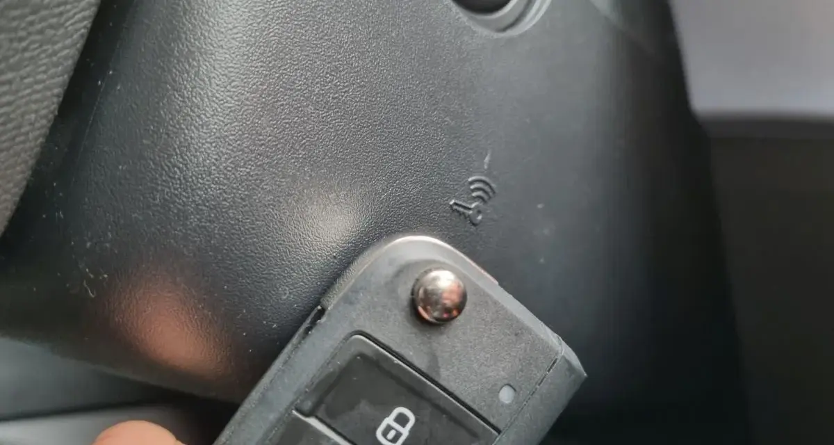 Kluczyk samochodowy z funkcją keyless go w pobliżu przycisku start.