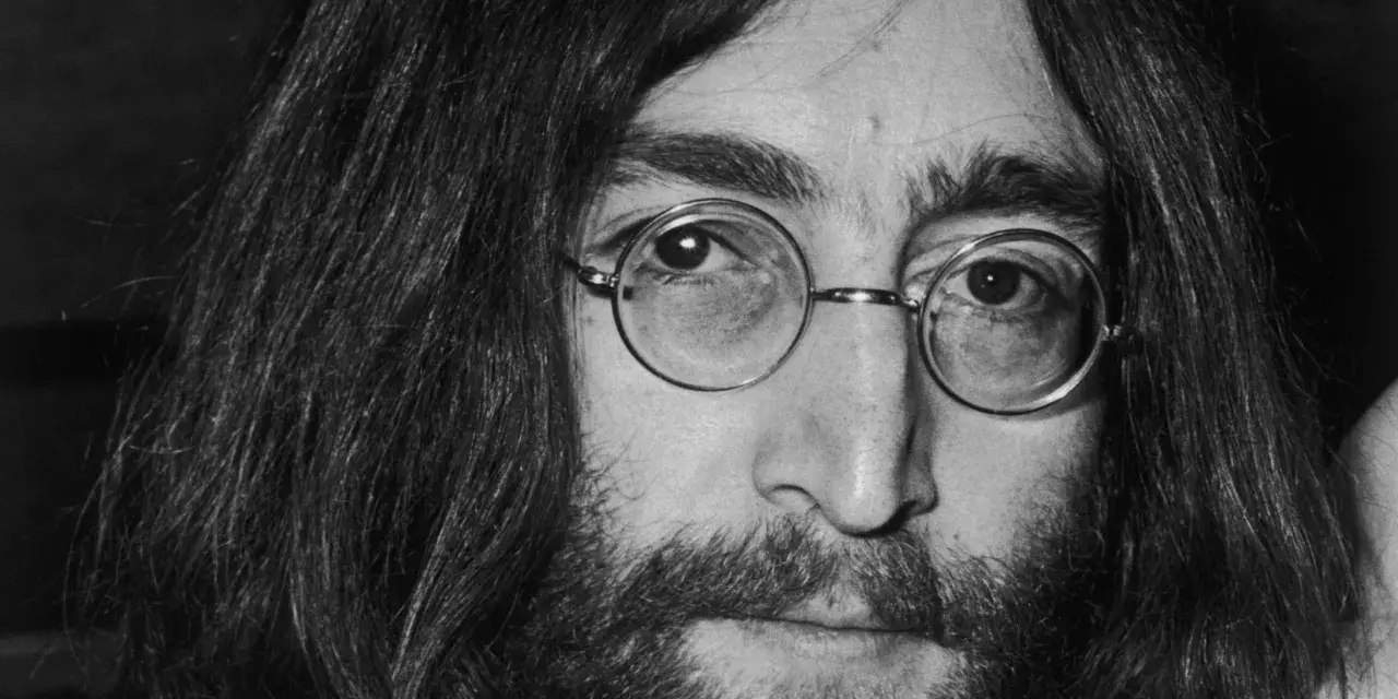 Nahaufnahme von John Lennon III. mit runden Brillengläsern und Bart.