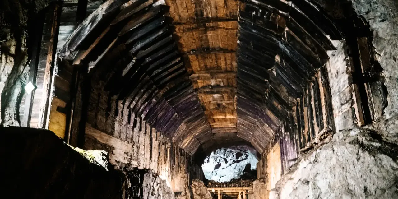 Wnętrze kopalni, drewniane wsporniki tworzą tunel, który prowadzi do jasnego otworu. To część kompleksu Rize.