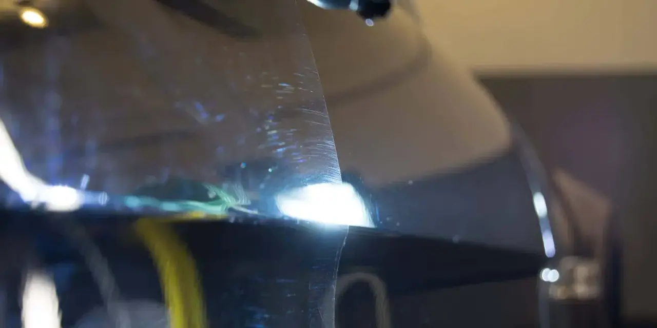 Widoczne rysy na lakierze ciemnego auta, które można usunąć, ucząc się jak wypolerować auto.