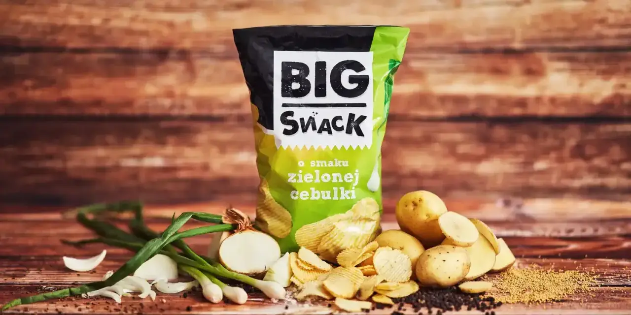 Reklamowa fotografia chipsów Big Snack o smaku zielonej cebulki, z ziemniakami i cebulką.