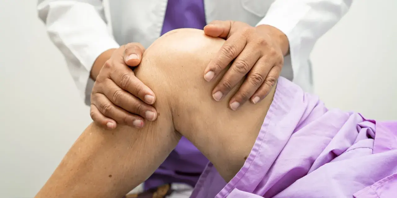 Lekarz bada kolano pacjenta, podejrzewając zerwane ACL. Wyniki rezonansu pokażą dokładny stan.