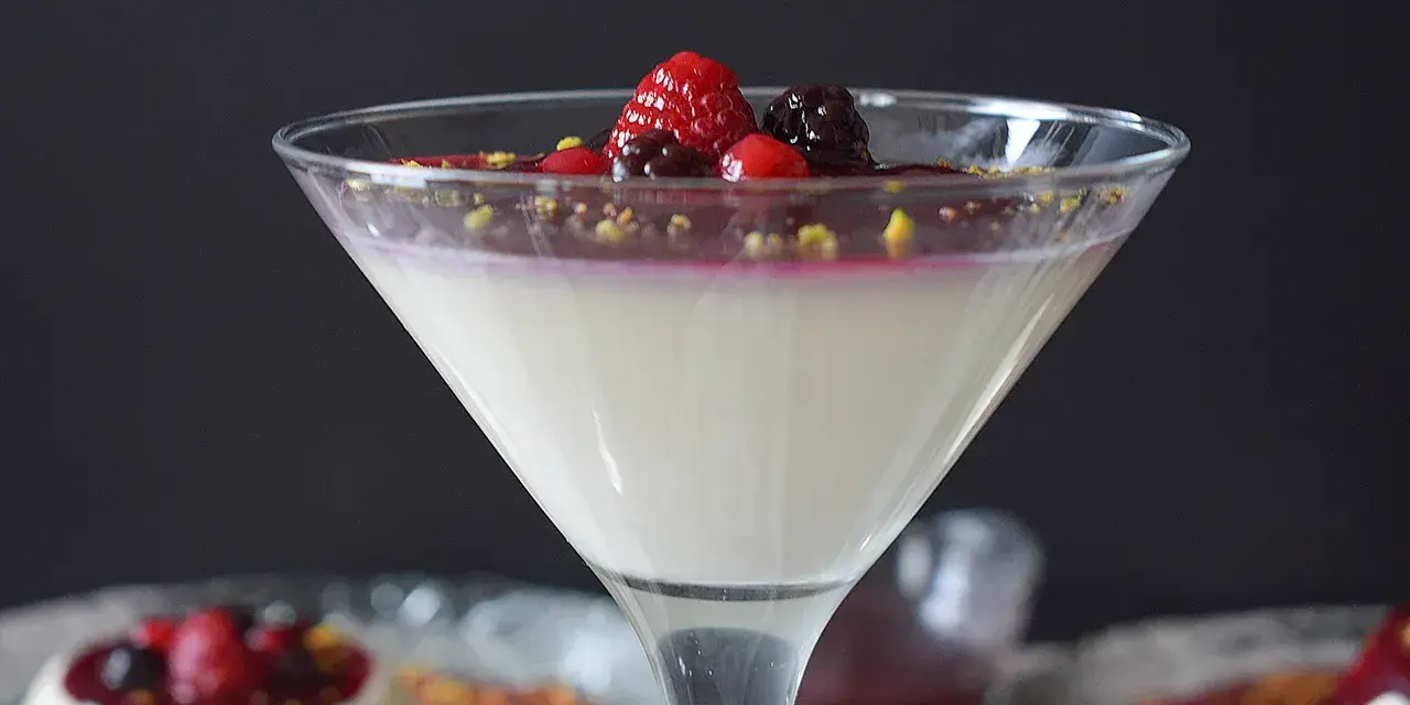 Deliciosa panna cotta receta, cremosa y adornada con frutos rojos y pistachos. Un postre elegante.