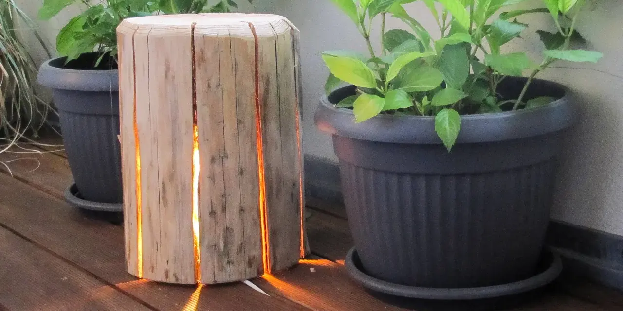 Un tronco di legno con fessure illuminate, un'idea creativa per come costruire una fioriera in legno.