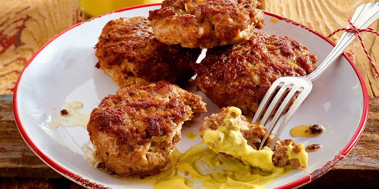 Leckere Frikadellen, goldbraun gebraten, mit Senf auf einem Teller. Ein perfektes Frikadellen Rezept für jeden Anlass.