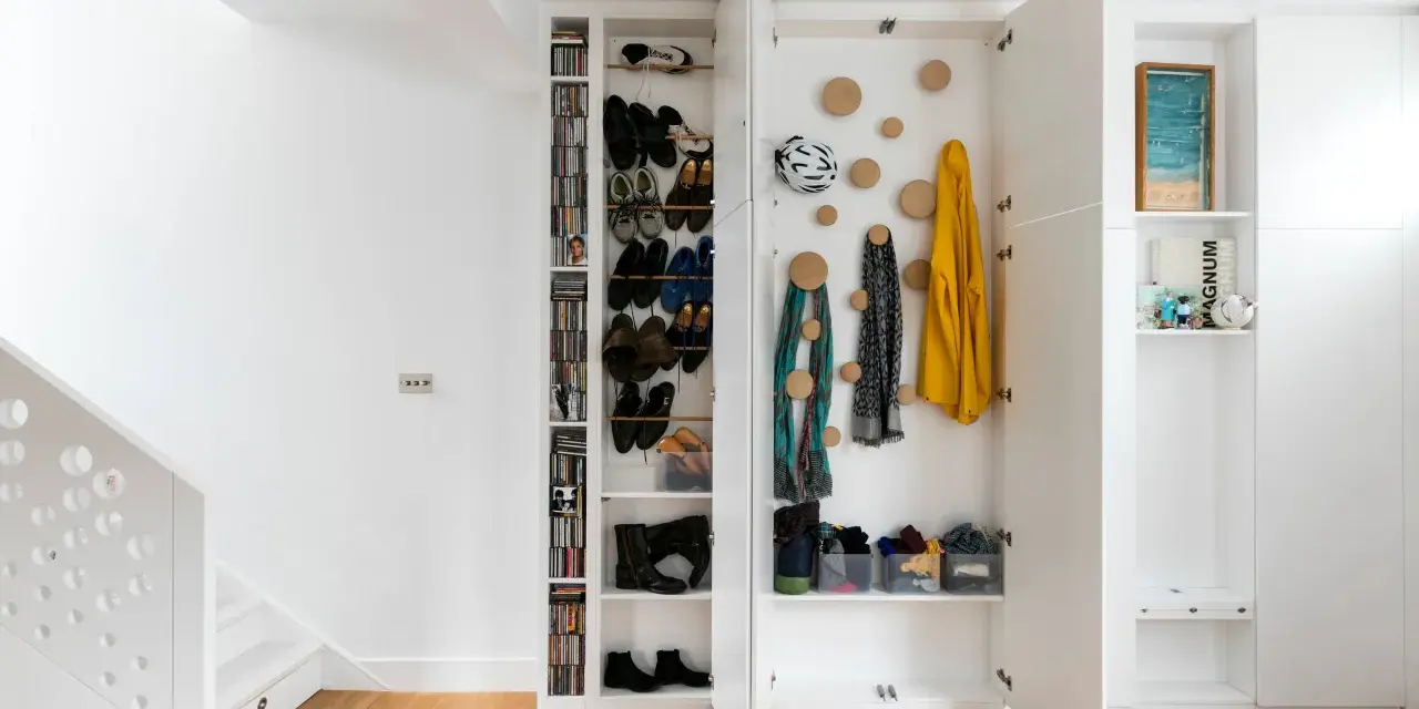 Moderne Garderobe Ideen: Offene Fächer mit Schuhen, Jacken und Schals. Ein Fahrradhelm hängt an der Wand.