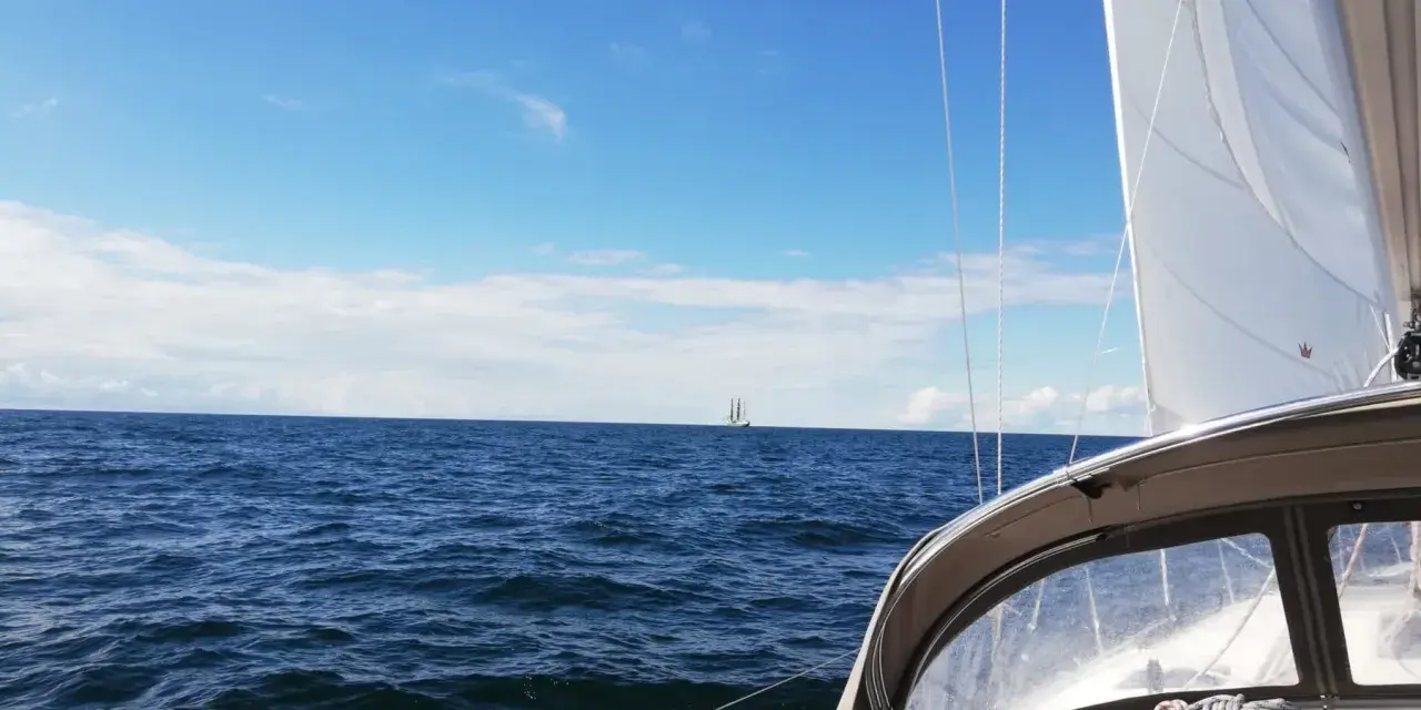 Segeln in Deutschland: Ein Segelboot gleitet über das Meer, im Hintergrund ein weiterer Segler unter blauem Himmel.