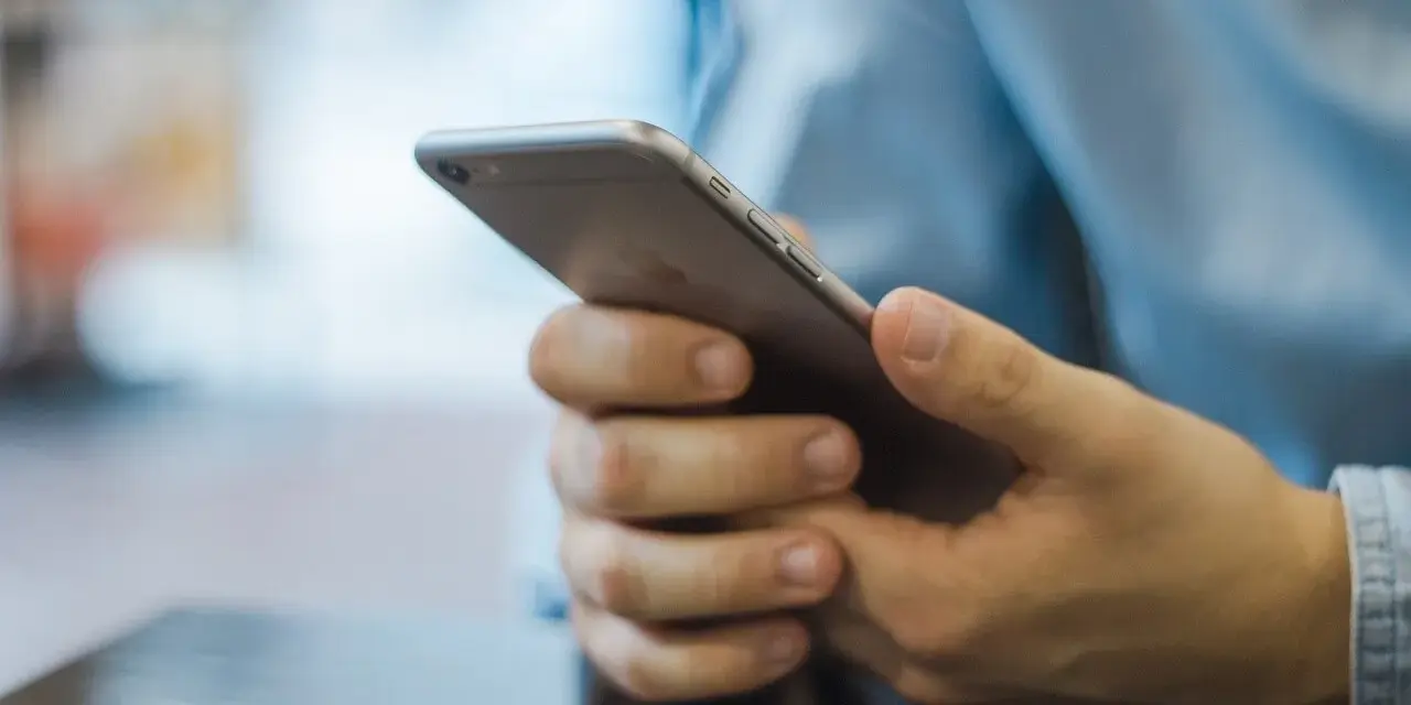 Dłonie trzymające smartfon, szukające inspiracji, jak zacząć rozmowę na Badoo.