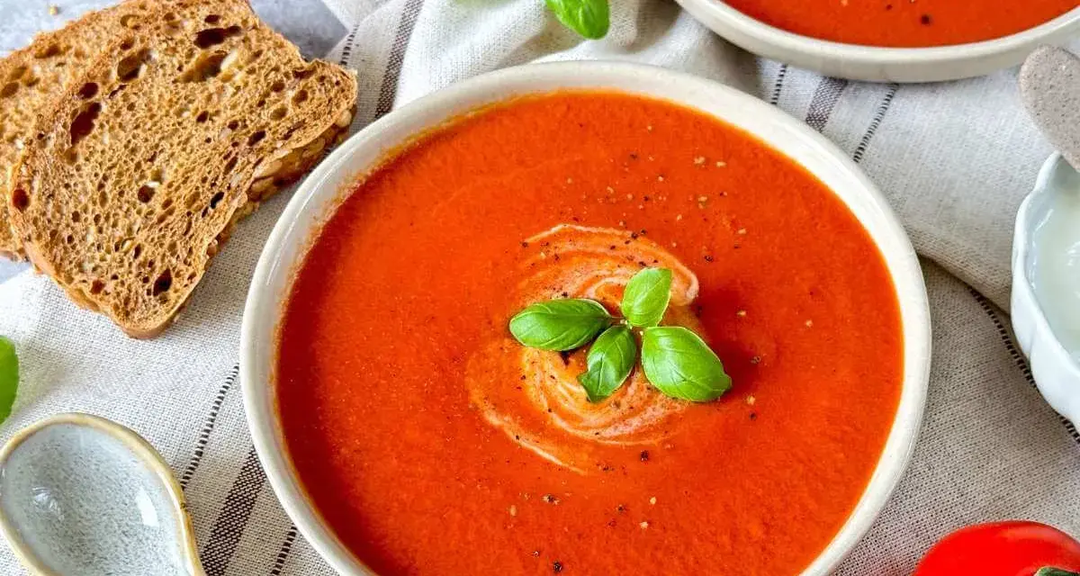 Cremige Tomatensuppe, ein tolles Rezept mit frischen Tomaten, garniert mit Basilikum und einem Klecks Sahne. Dazu knuspriges Brot.