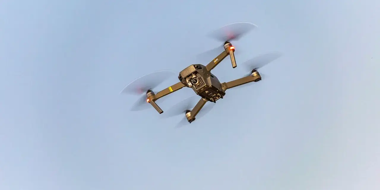 A drone flies in the sky, a reminder to check Maine drone laws before takeoff.