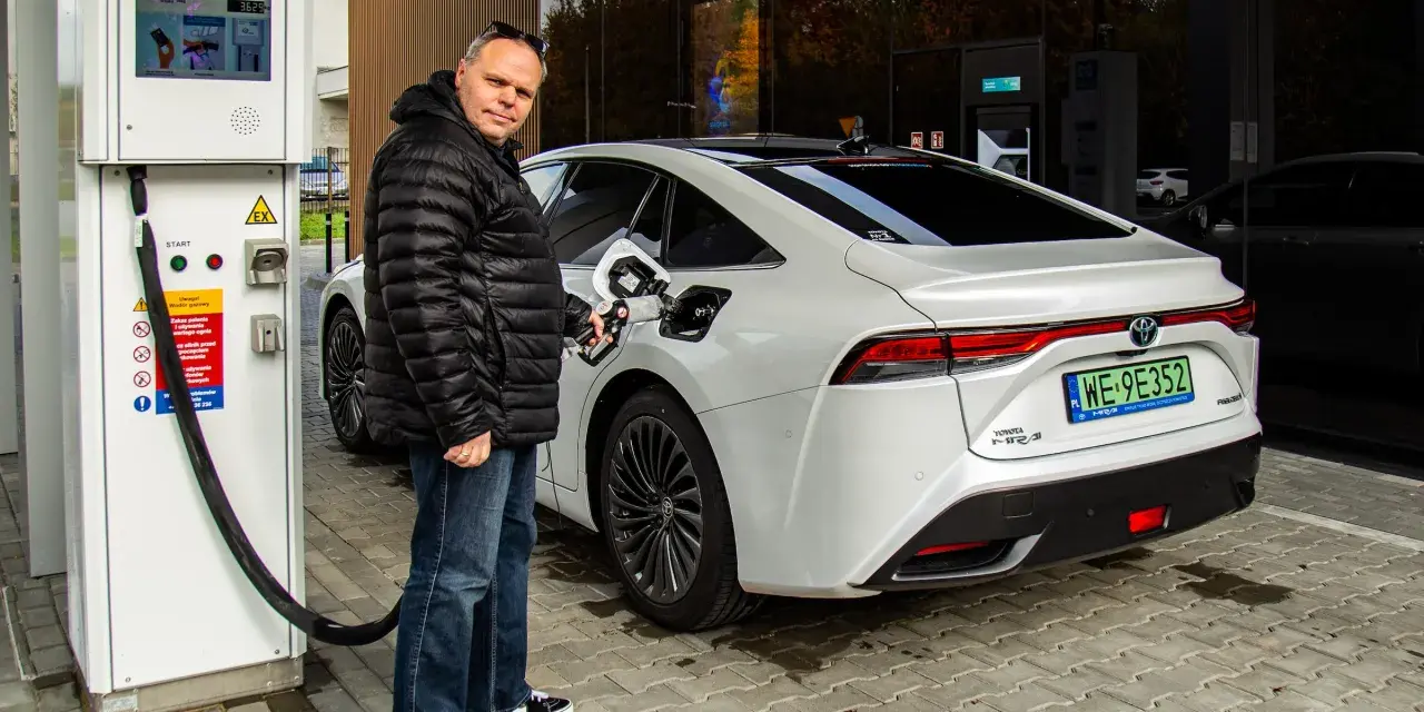 Mężczyzna tankuje białą Toyotę Mirai na jednej z pierwszych stacji wodorowych w Polsce.
