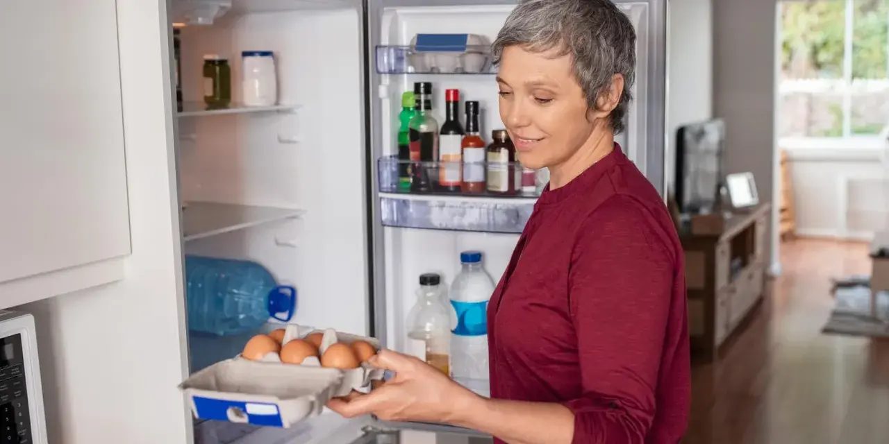 Frau holt Eier aus dem Kühlschrank. Nach einer Darmspiegelung ist leichte Kost wie Eier oft das erste Essen.