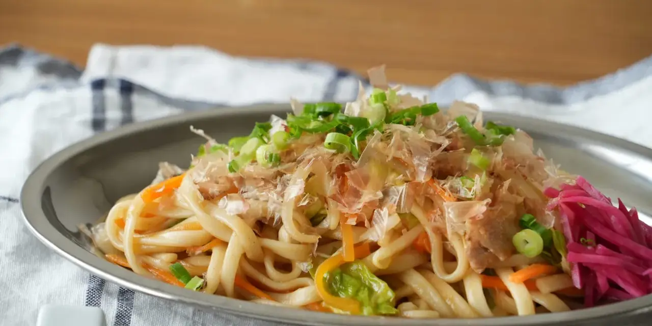 Udon z warzywami i szczypiorkiem, posypany płatkami katsuobushi. To właśnie katsuobushi co to jest, suszone płatki bonito, dodają daniu głębi smaku.