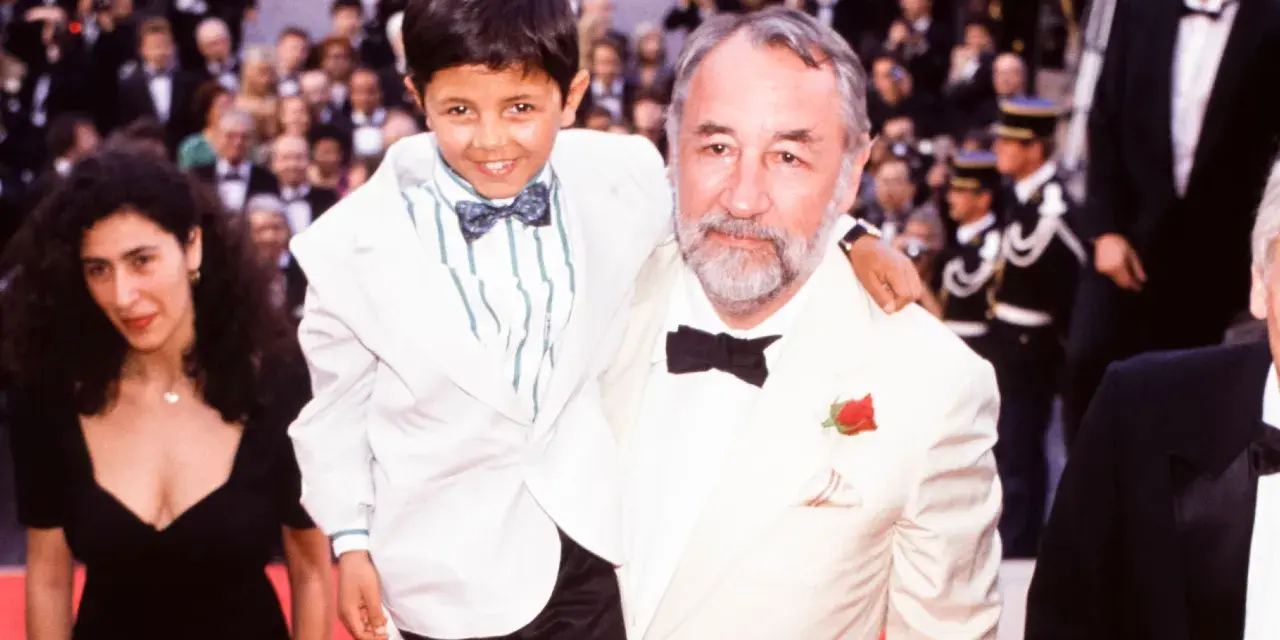 Un bambino sorridente, protagonista di "Nuovo Cinema Paradiso", abbracciato da un uomo con una rosa all'occhiello.
