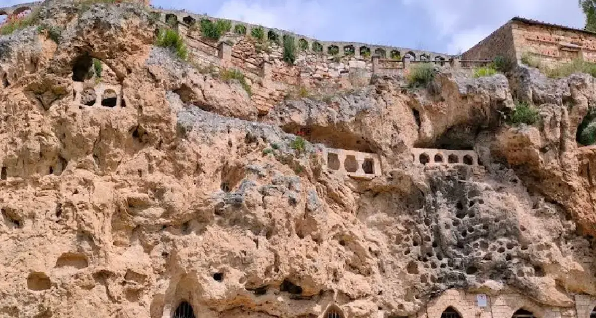 Antigua ciudad excavada en roca, con arcos y ventanas en las cuevas. Un lugar histórico que parece una cascada de piedra.
