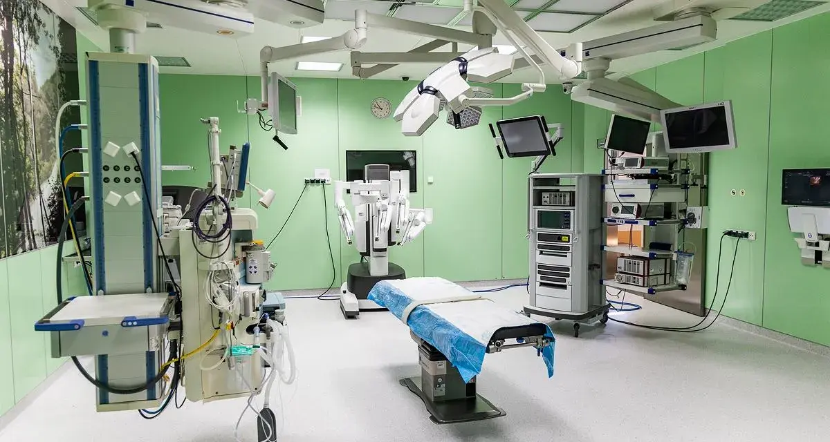 Nowoczesna sala operacyjna z robotem da Vinci, stołem zabiegowym i aparaturą medyczną.