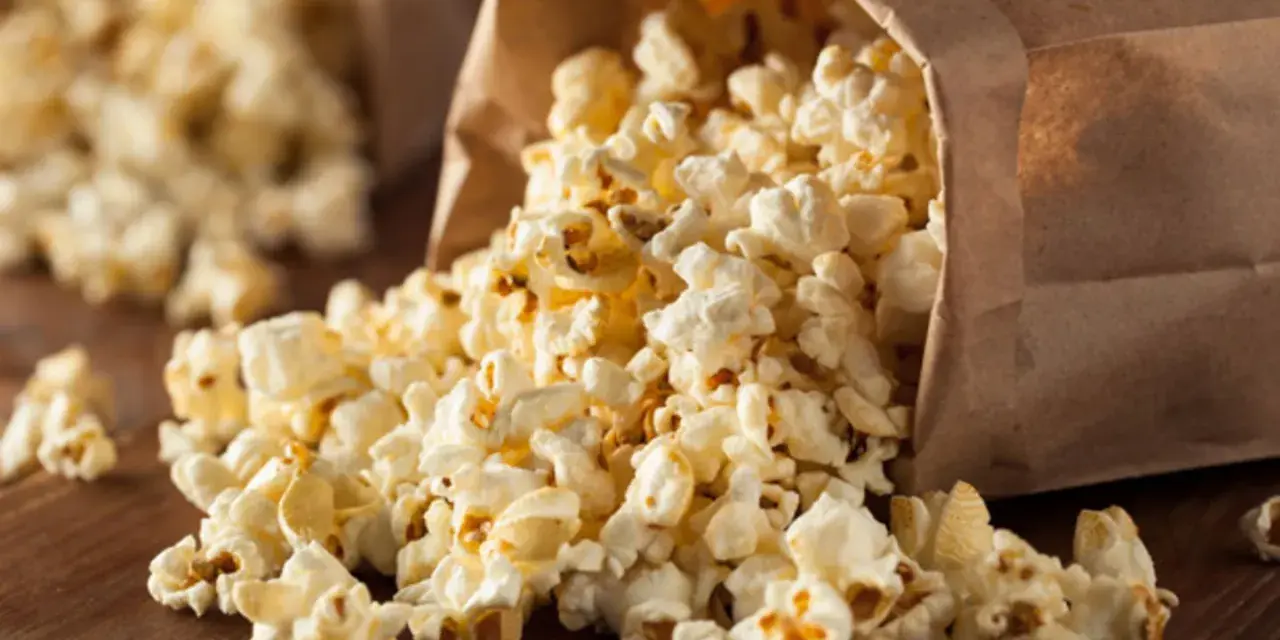 Popcorn rieselt aus einer Papiertüte. Ein perfekter, leichter Snack für zwischendurch.