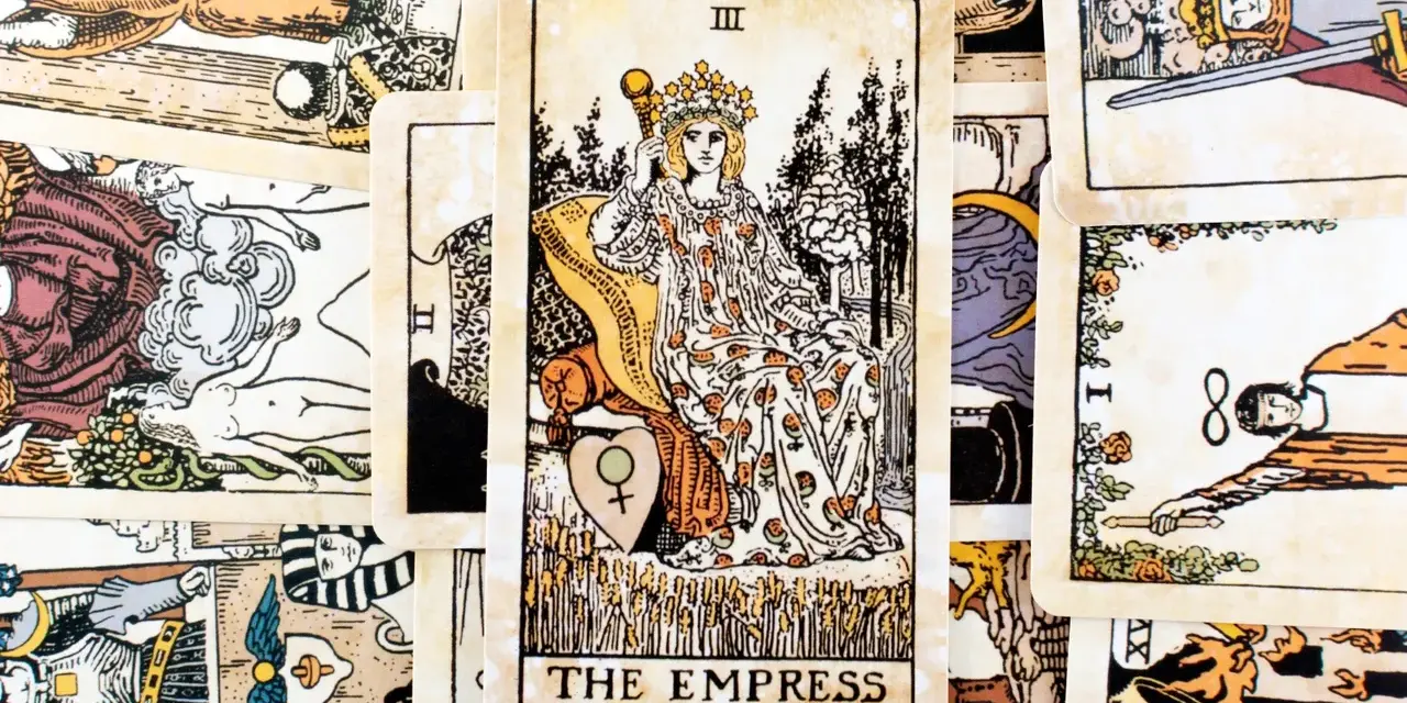 Karta cesarzowa tarot, przedstawiająca kobietę w koronie na tronie, otoczona innymi kartami.