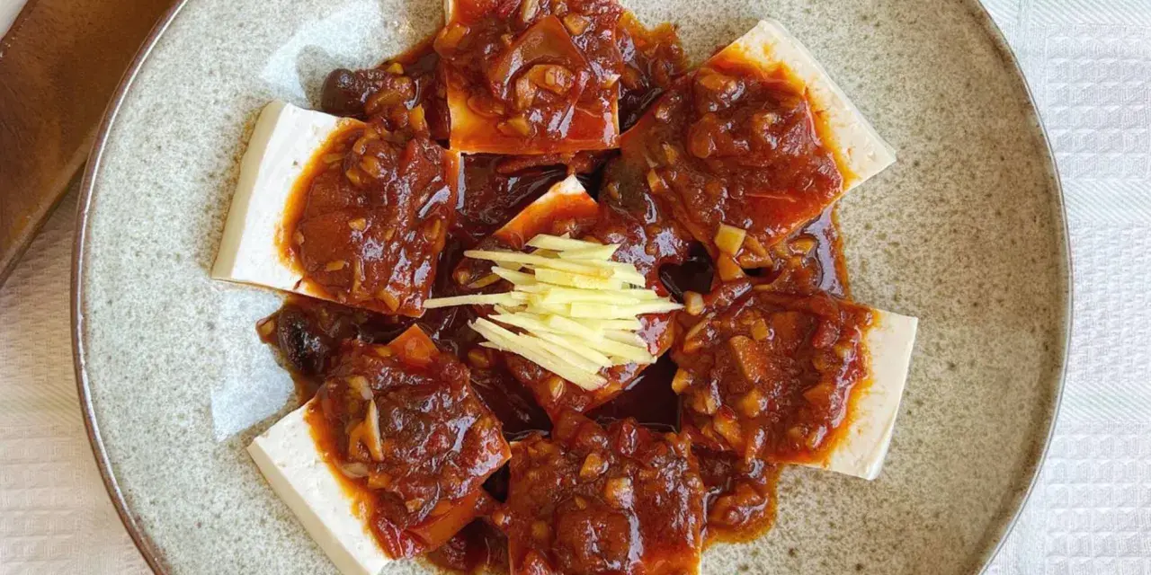 Tofu comida servida en un plato con salsa picante y jengibre rallado.