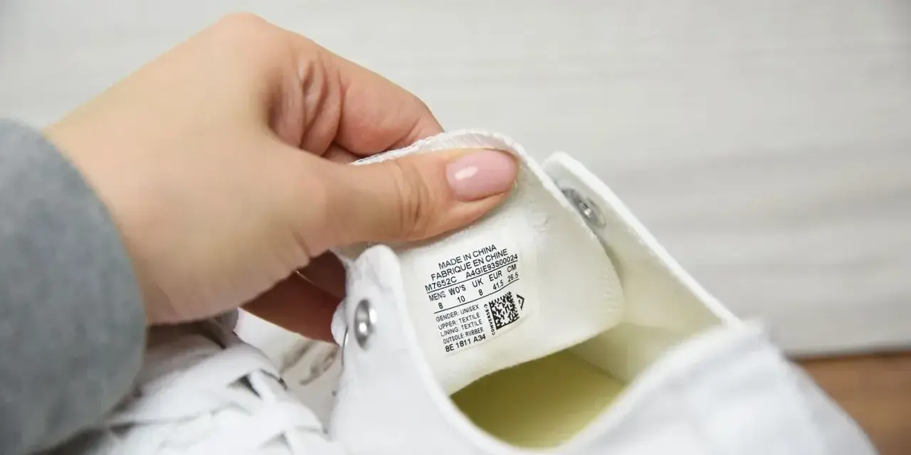 Porównanie converse oryginalne a podróbki. Dłoń pokazuje metkę z rozmiarem na białym bucie.