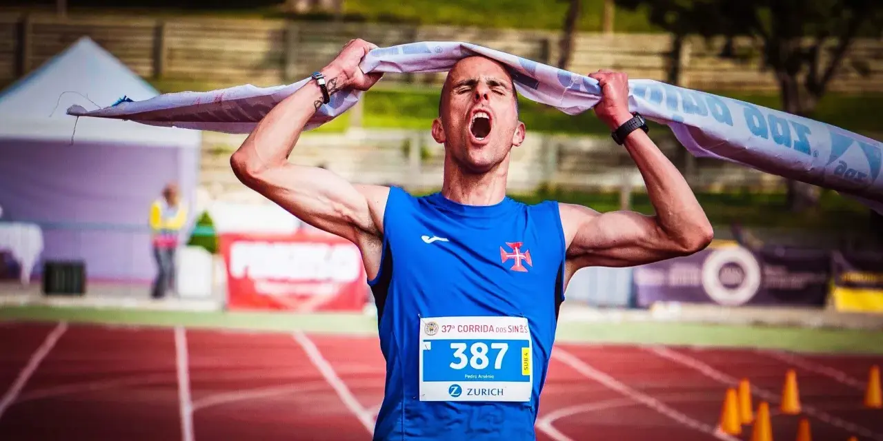 Atleta exhausto, con la boca abierta y una toalla sobre la cabeza, celebra el fin de correr una maratón.