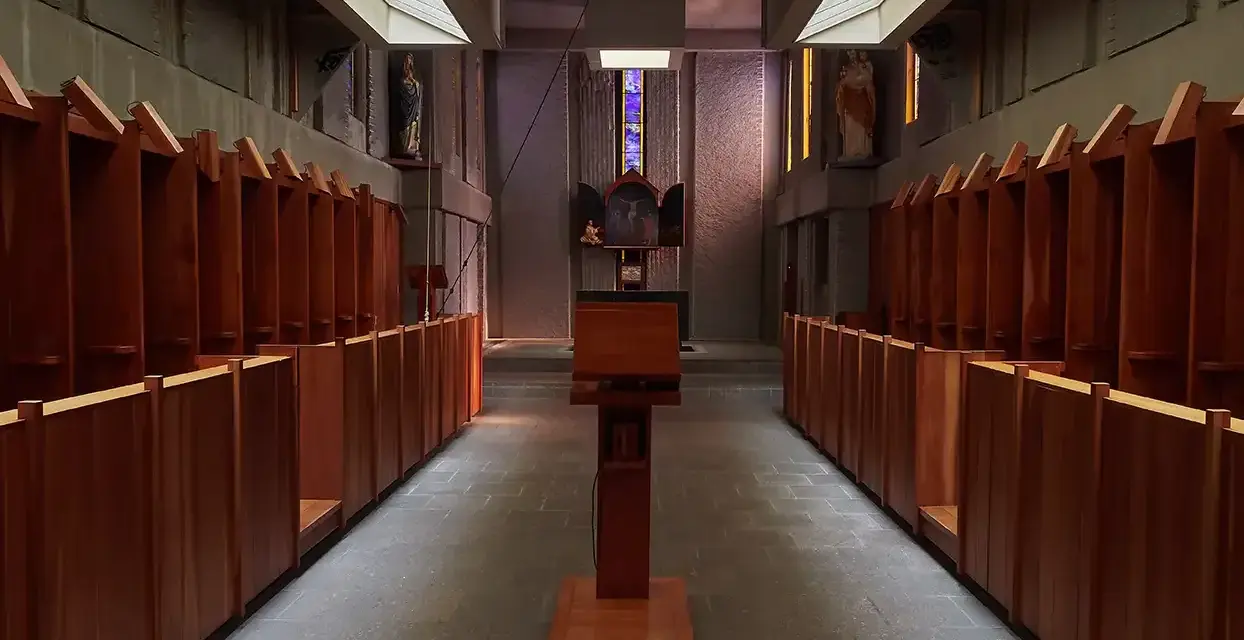 Rows of wooden stalls line the interior of a Carthusian monastery, leading towards an altar.