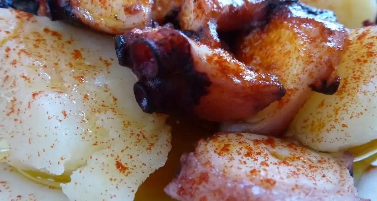 Pulpo con cachelos, un plato gallego tradicional. Tentáculos de pulpo cocidos y trozos de patata, todo espolvoreado con pimentón y aceite de oliva.