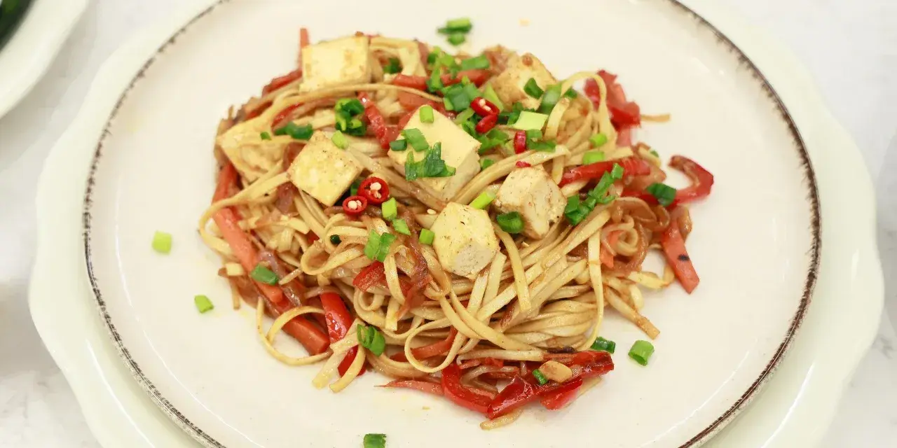Pyszny makaron chow mein z kostkami tofu, papryką i szczypiorkiem.