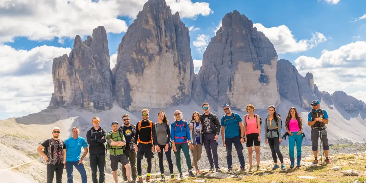 Grupa przyjaciół na tle Tre Cime di Lavaredo podczas niezapomnianego trekkingu w Dolomitach.