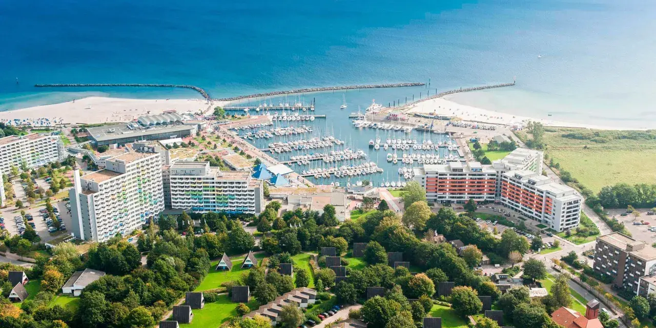 Luftaufnahme eines Yachthafens mit vielen Booten. Im Hintergrund der Strand und das Meer. Die Schifffahrt von Damp nach Laboe ist hier gut zu erkennen.