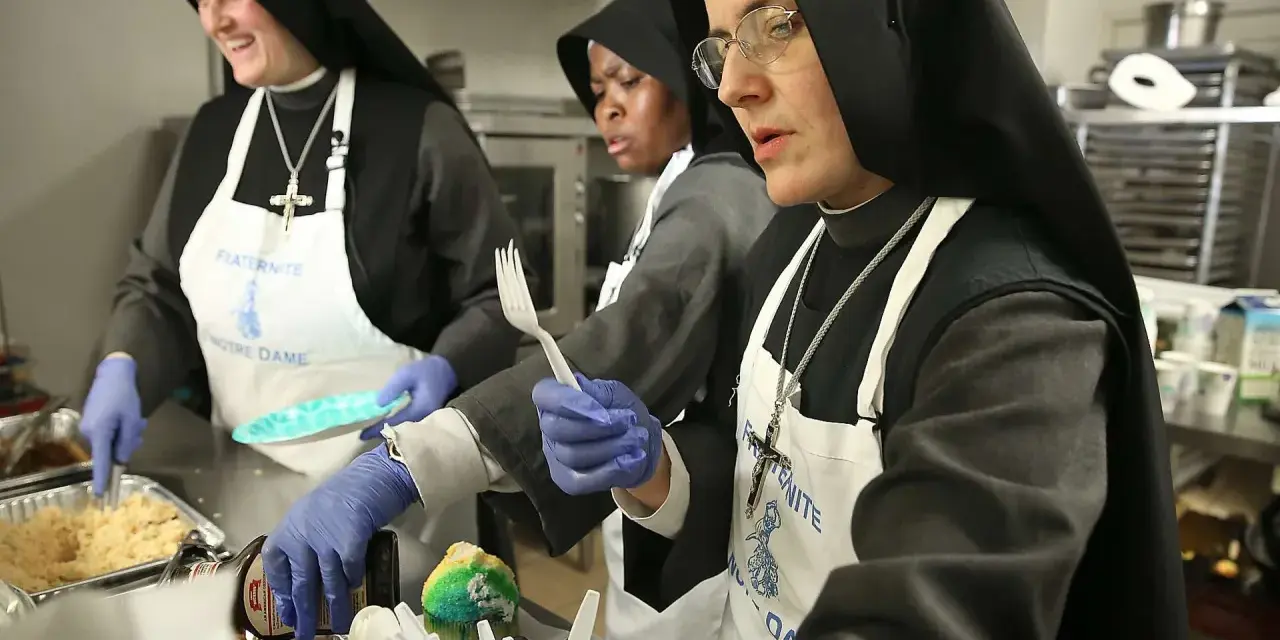 Nuns in a kitchen preparing food. One nun smiles while serving, another holds a fork, and a third looks on. This scene might answer the question: do nuns eat meat?