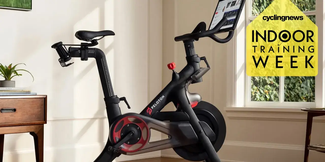 A Peloton bike, perfect for indoor cycling vs spinning, sits in a bright room. A yellow graphic promotes "Indoor Training Week.