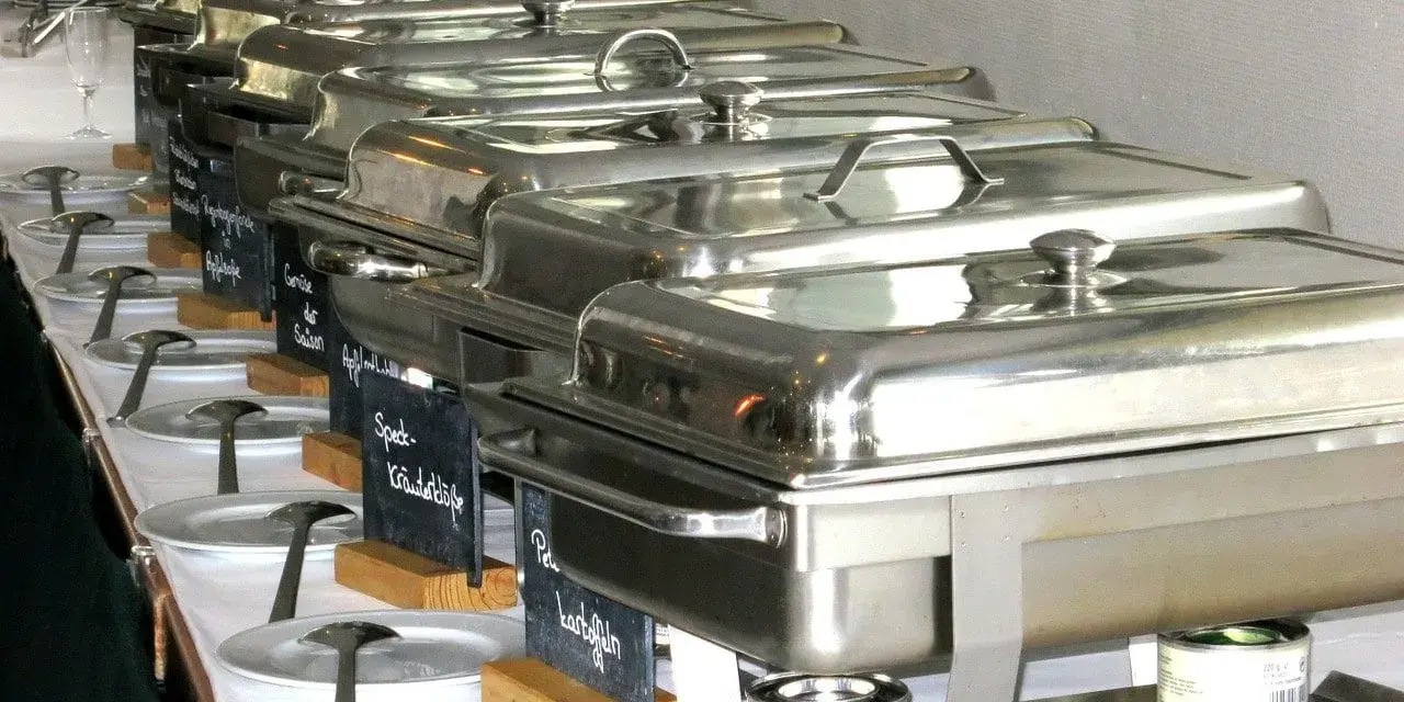 Długi rząd podgrzewaczy z jedzeniem, gotowych do serwowania. To świetny pomysł, jak otworzyć catering i zaimponować gościom.