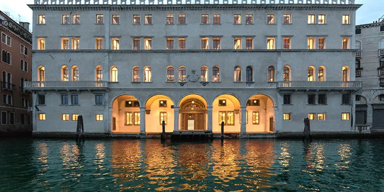 Palazzo Tedeschi a Venezia, con le sue arcate illuminate e il riflesso sull'acqua, evoca un'atmosfera magica.