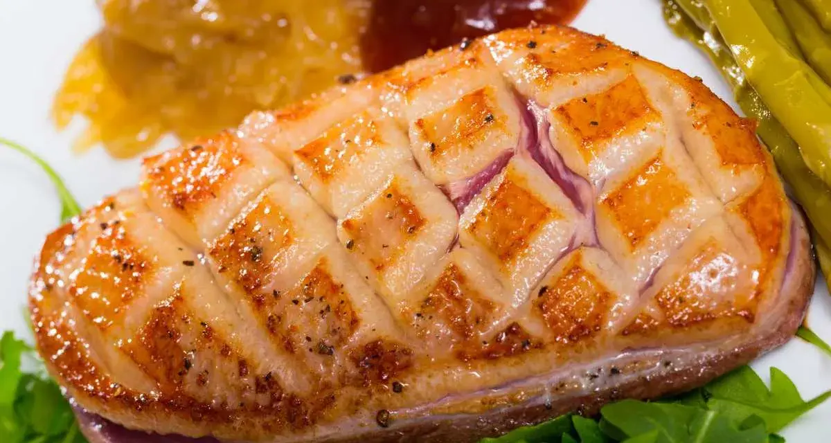 Magret de pato perfectamente cocinado, con piel crujiente y jugoso por dentro, acompañado de espárragos y compota.