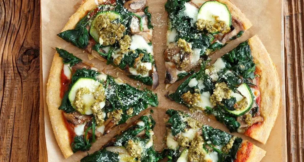 Pyszna pizza ze szpinakiem, cukinią i pieczarkami, polana zielonym pesto. Idealna na lekki obiad.