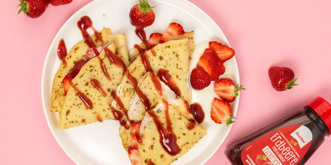Zarte crepes ohne zucker, garniert mit frischen Erdbeeren und Erdbeer-Topping. Ein Genuss für alle, die es süß, aber zuckerarm mögen.