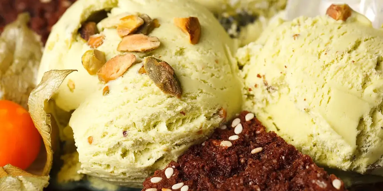 Veganes Eis selber machen: Cremiges Pistazieneis mit Nüssen und Schokostückchen, garniert mit Physalis.
