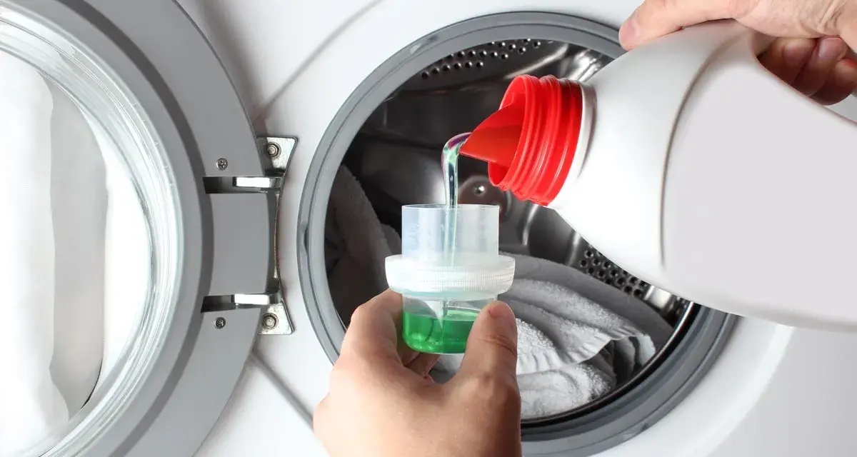 Versando detersivo liquido in un misurino per lavatrice. Ideale per capi delicati, cosa lavare a 20 gradi per preservare i colori.