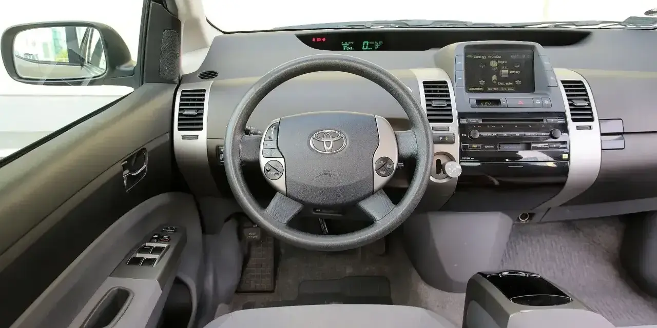 Wnętrze Toyoty Prius 2 z kierownicą, panelem radia i ekranem.