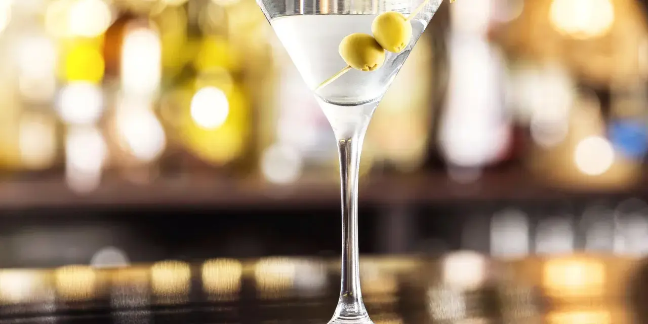 Elegancki gin z wermutem, ozdobiony dwiema oliwkami, czeka na Ciebie przy barze.
