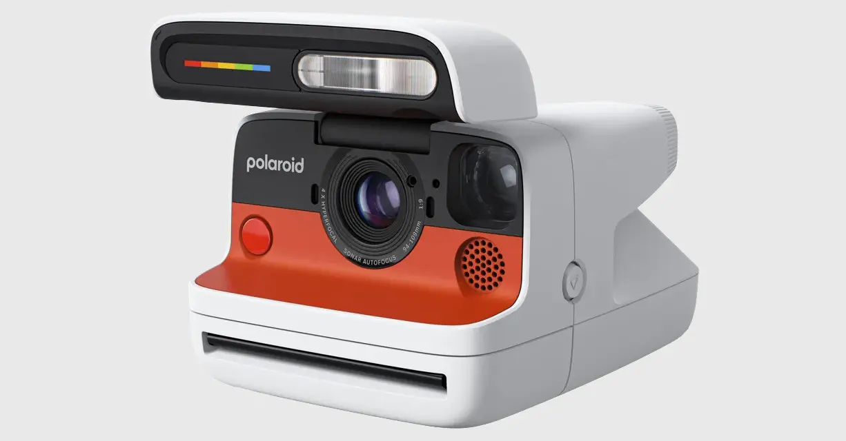 Nowoczesny aparat Polaroid z pomarańczowym akcentem i tęczowym paskiem na lampie błyskowej. To właśnie polaroid, co to za magia!