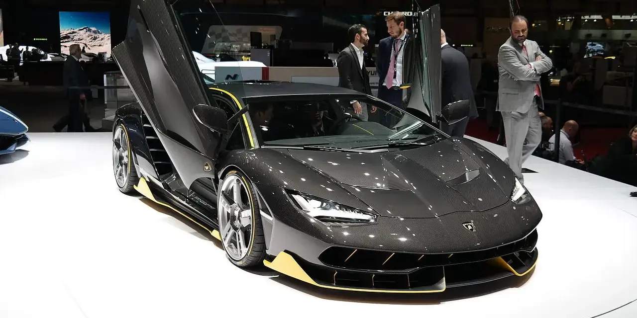 Ciemnoszary Lamborghini z otwartymi drzwiami, żółte akcenty. Zastanawiasz się, ile kosztuje Lamborghini Urus? Ten model to marzenie.