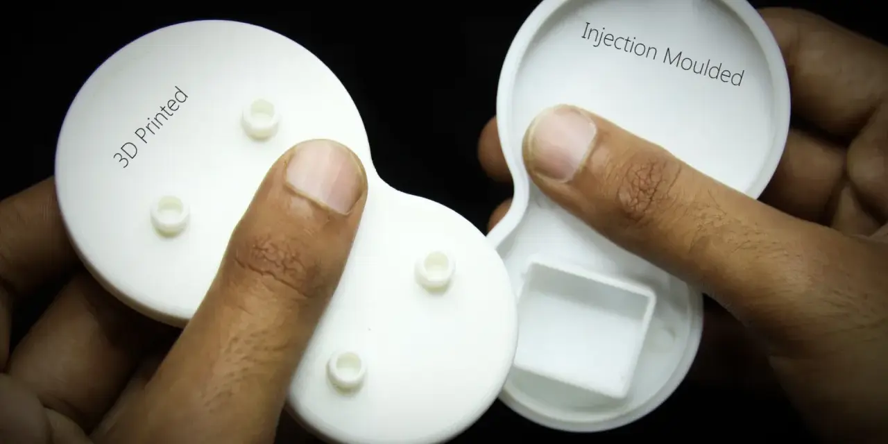 Hands hold two white plastic parts, one labeled "3D Printed" and the other "Injection Moulded," showcasing the difference between the two manufacturing methods.