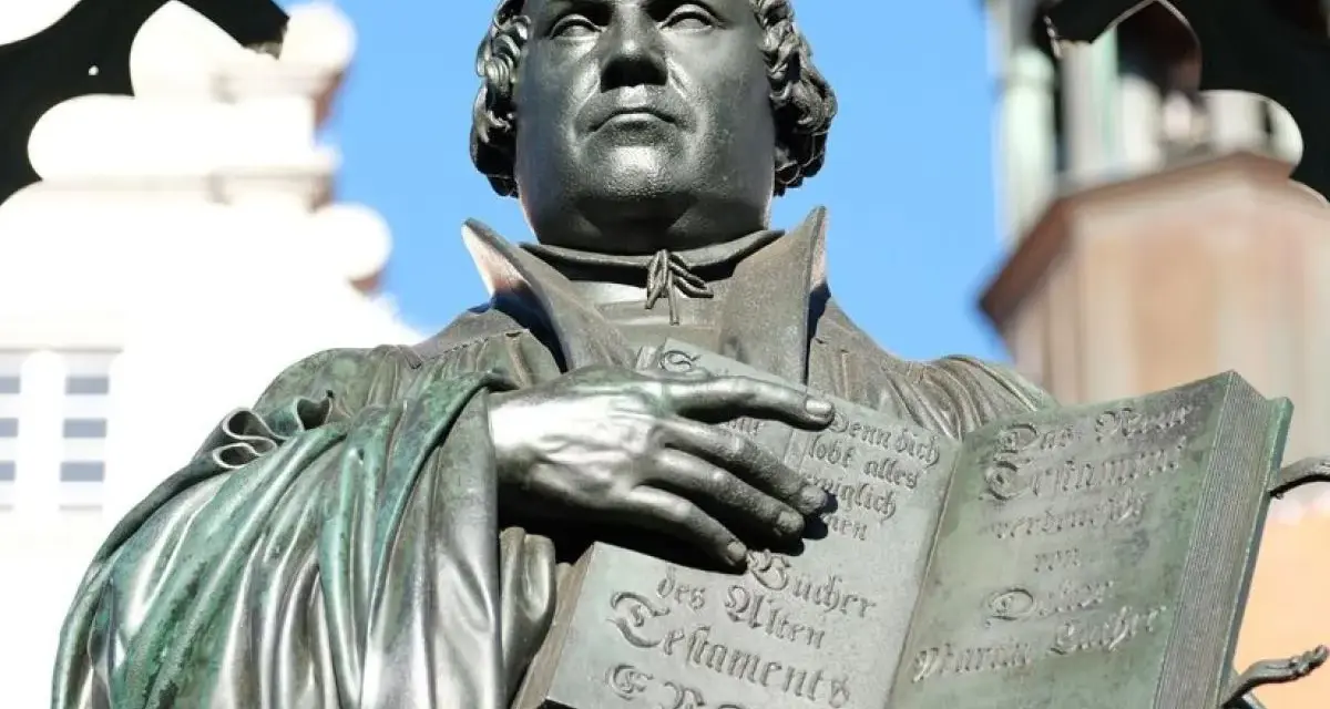 Martin Luther hält eine Bibel. Er erinnert uns daran, wer am Reformationstag frei hat.